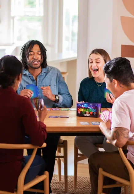 Group of people sitting around a table playing doomlings
